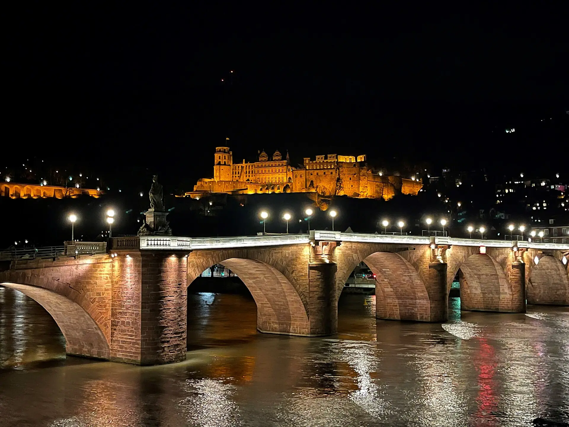 Angestrahltes Heidelberger Schloss über der beleuchteten Alten Brücke bei Nacht